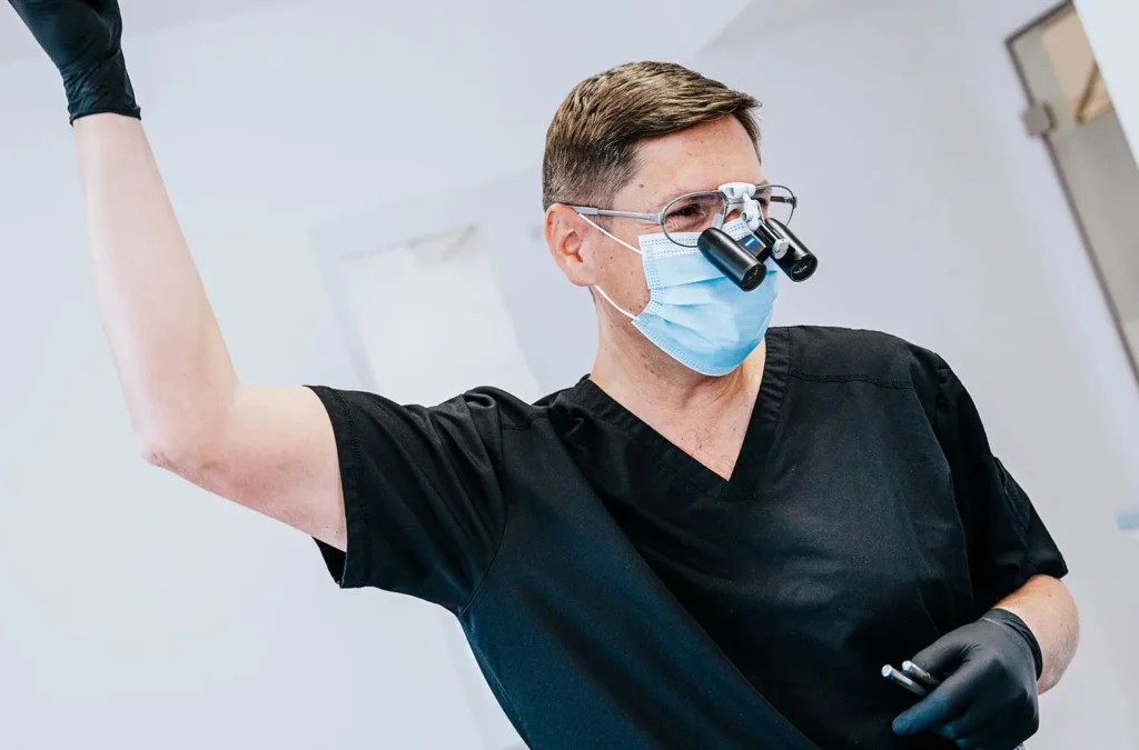 Dr. Jochen K. Alius mit Lupenbrille und OP-Maske bei einer Implantatbehandlung in der Praxisklinik in der Mauthalle – Implantologie in Nürnberg